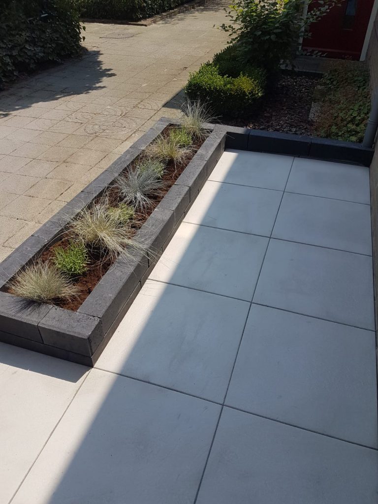 Voortuin met sierbestrating 60 × 60 cm en plantenbakken van linia's