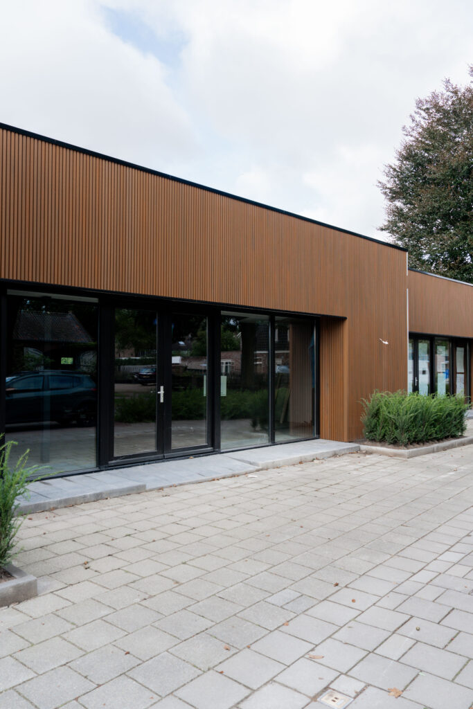 Gevel met verticale houtlook-gevelbekleding boven glazen puien