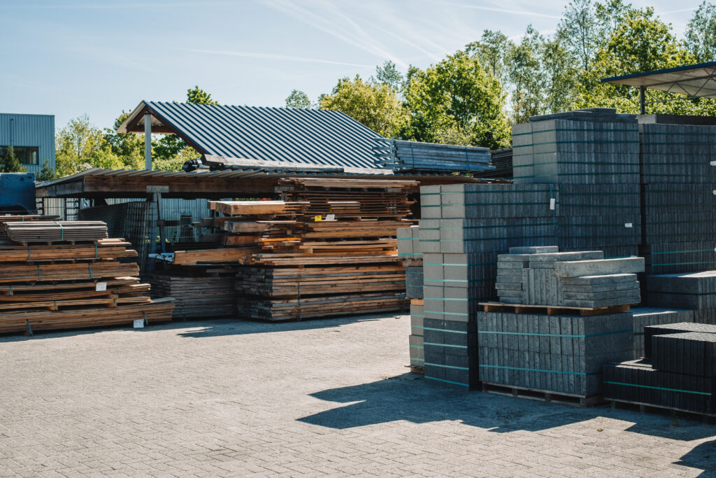 De werf van Daams aan de Dragonder 38 met stapels hout en bestratingsmateriaal