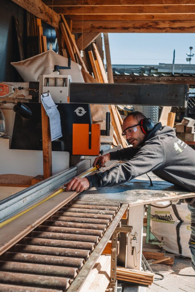 Medewerker meet een plank af bij de zaagmachine in de eigen zagerij van Daams